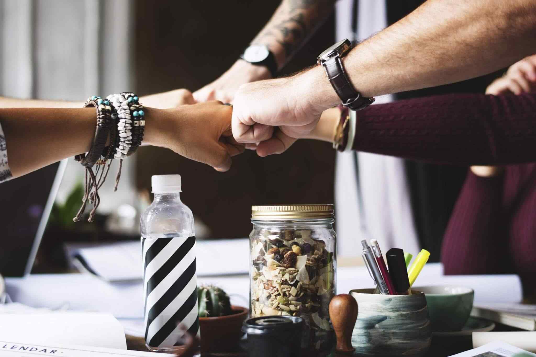 Team fist bump over office table.