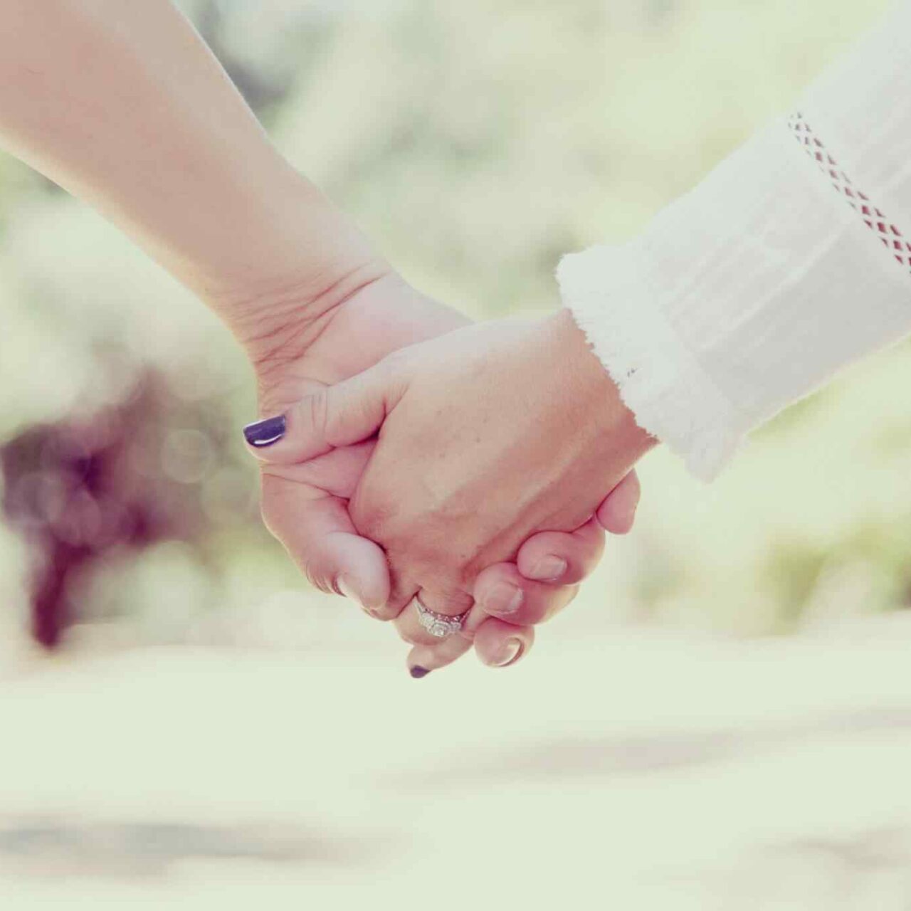 Two people holding hands outdoors.