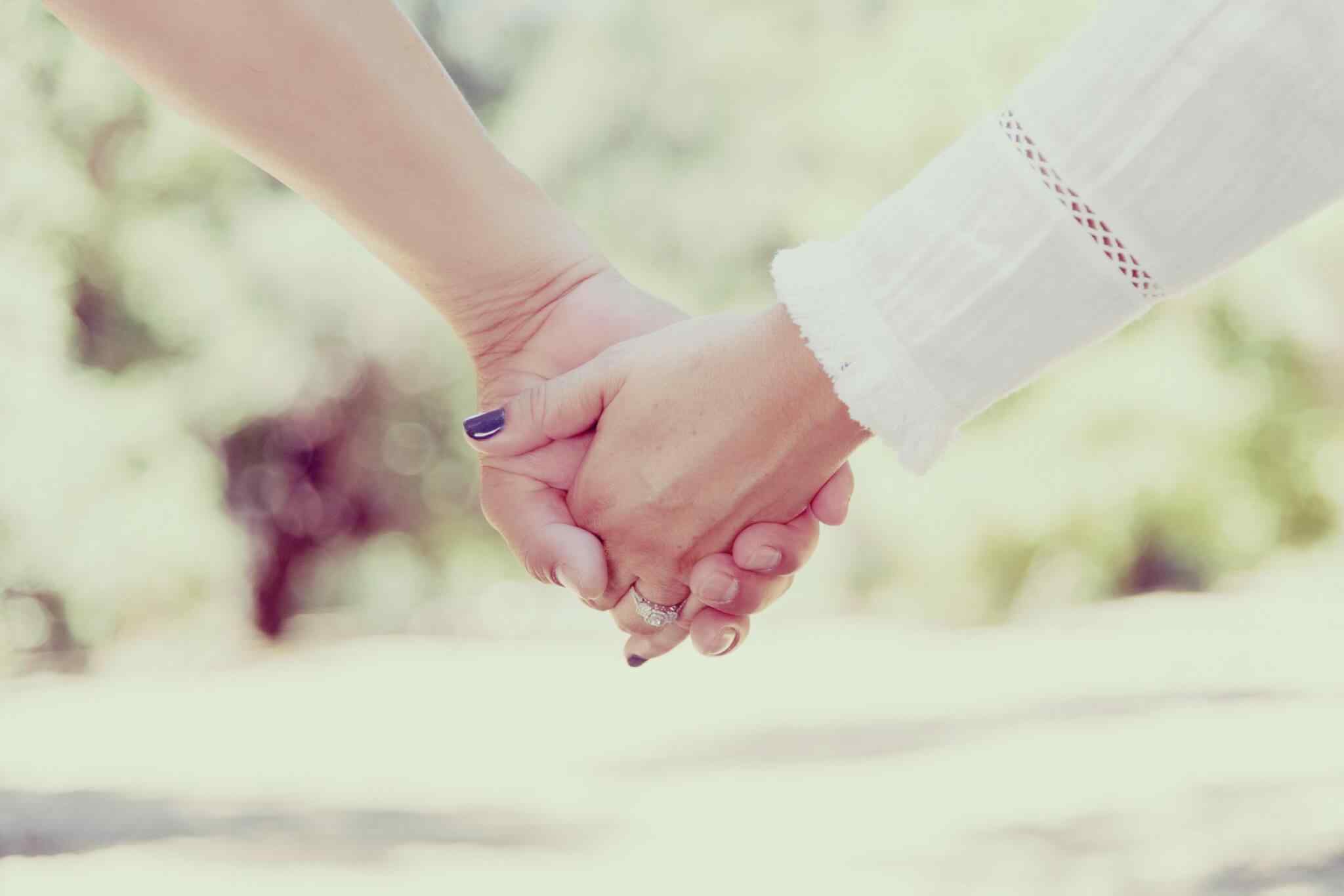 Two people holding hands outdoors.