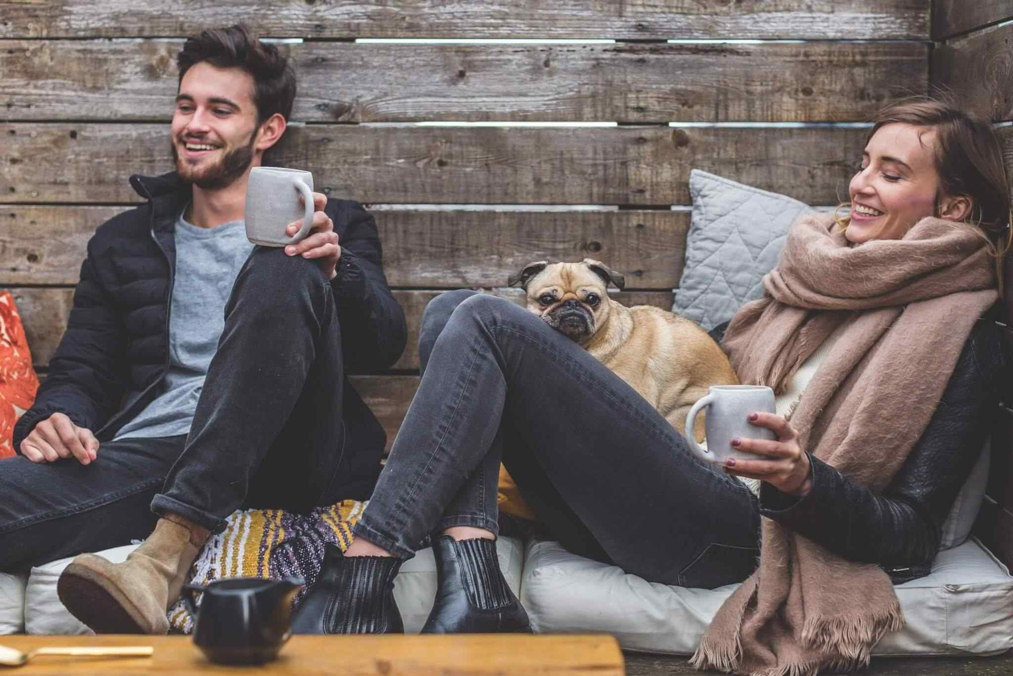 Couple relaxing with pug and coffee.