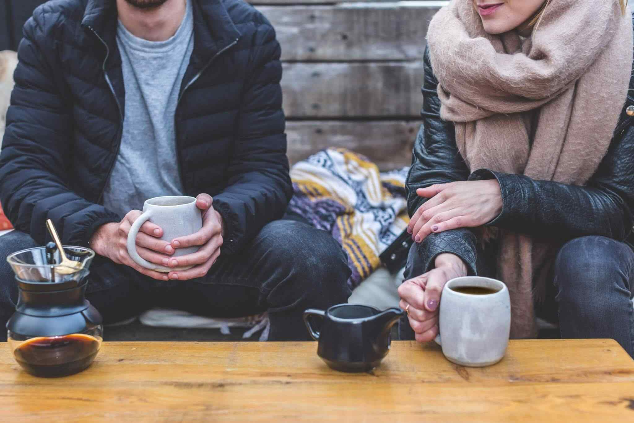 Two people sitting with coffee mugs.