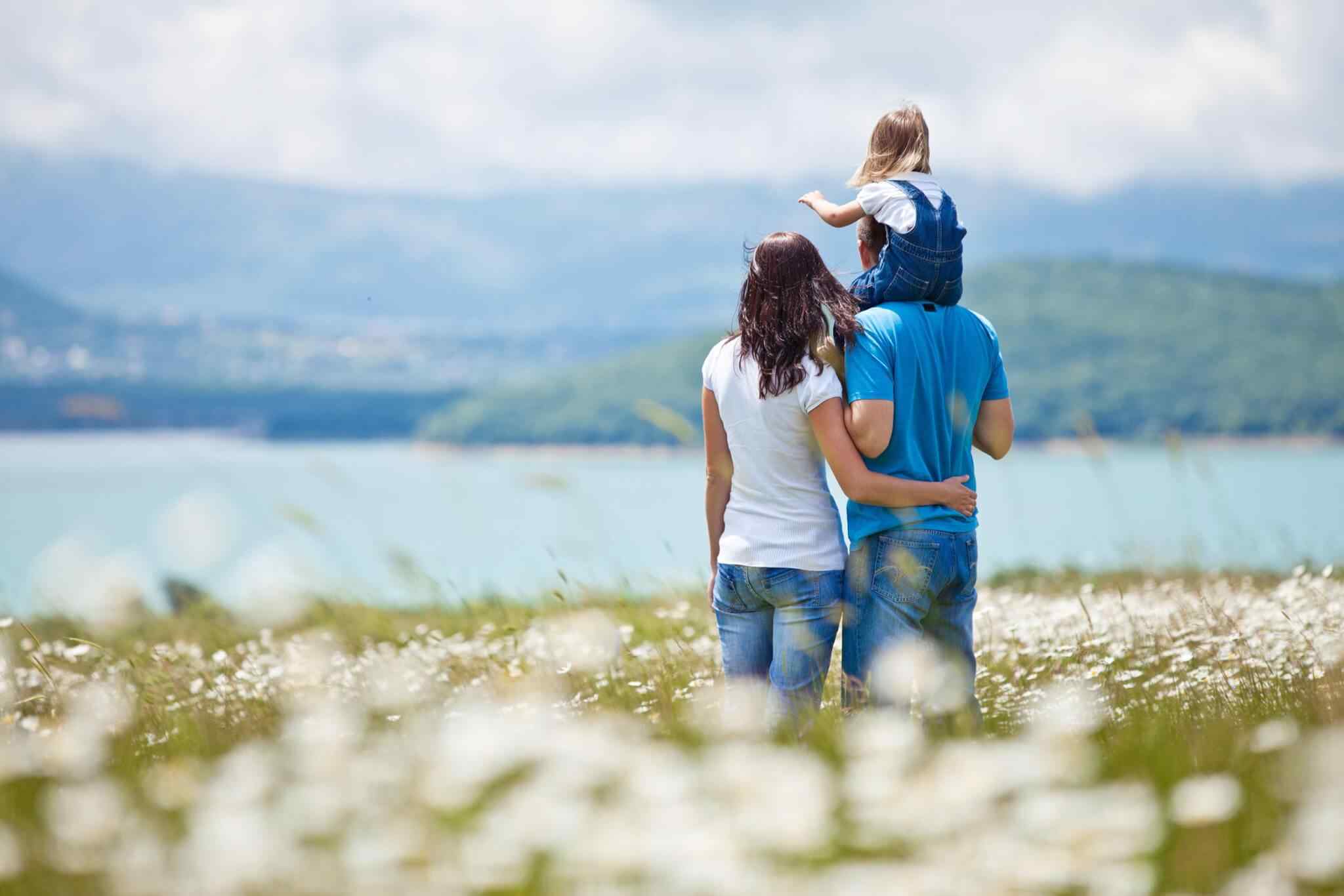 Family walking through a field by lake.