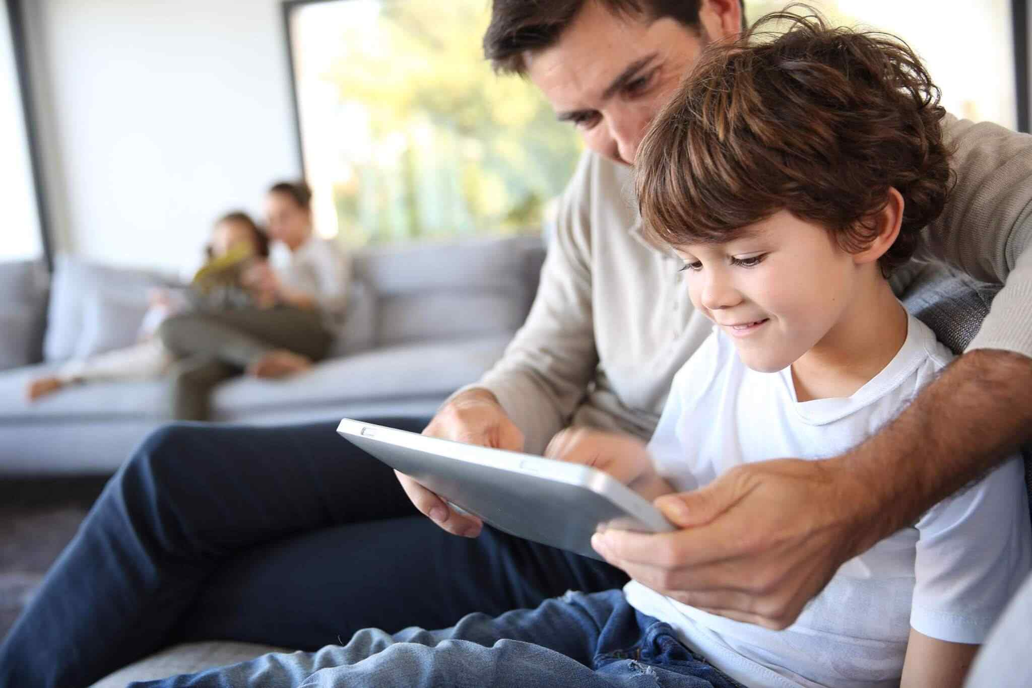 Father and son using tablet together, smiling.