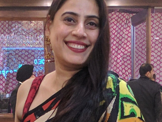 Smiling woman in colorful patterned attire.