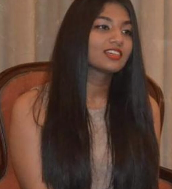 Woman with long hair, sitting indoors.