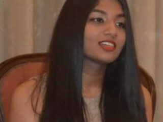 Woman with long hair, sitting indoors.