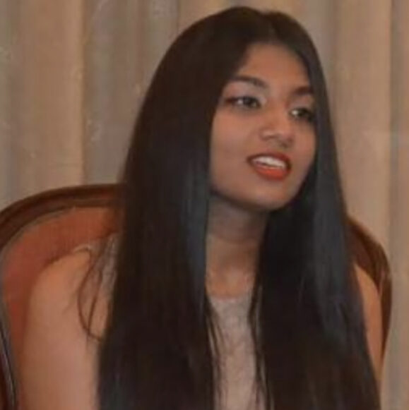 Woman with long hair, sitting indoors.