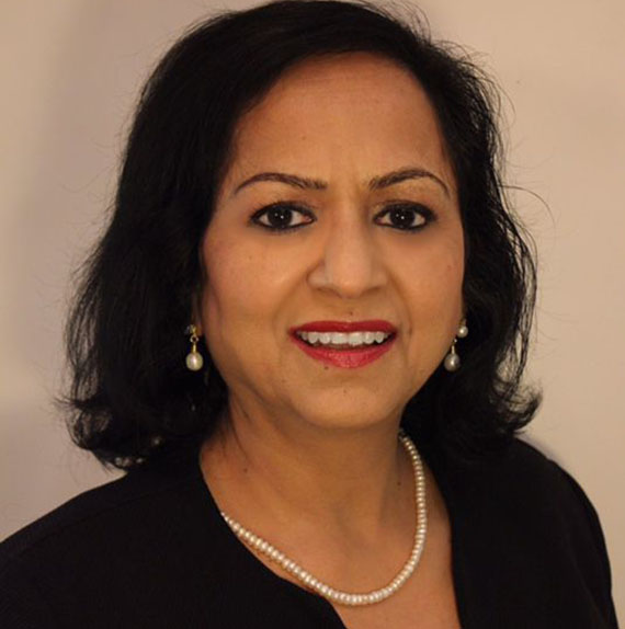 Woman smiling with pearl necklace and earrings.