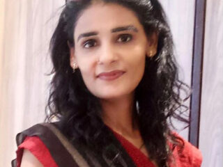 Woman wearing glasses and red outfit smiling.